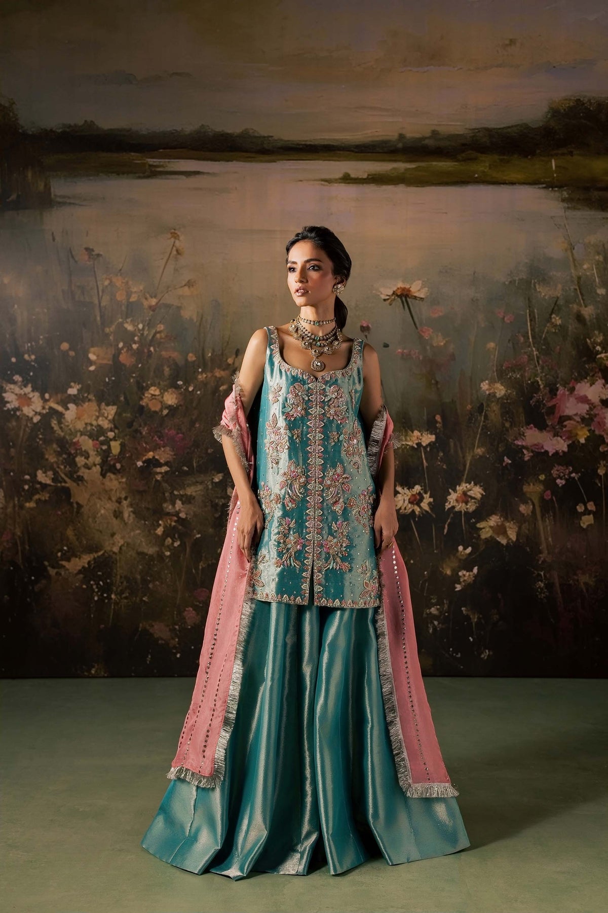 Woman wearing the Zonaira Ahmed Firouzeh turquoise tissue kurta and sharara with a peach-pink embellished dupatta, front view