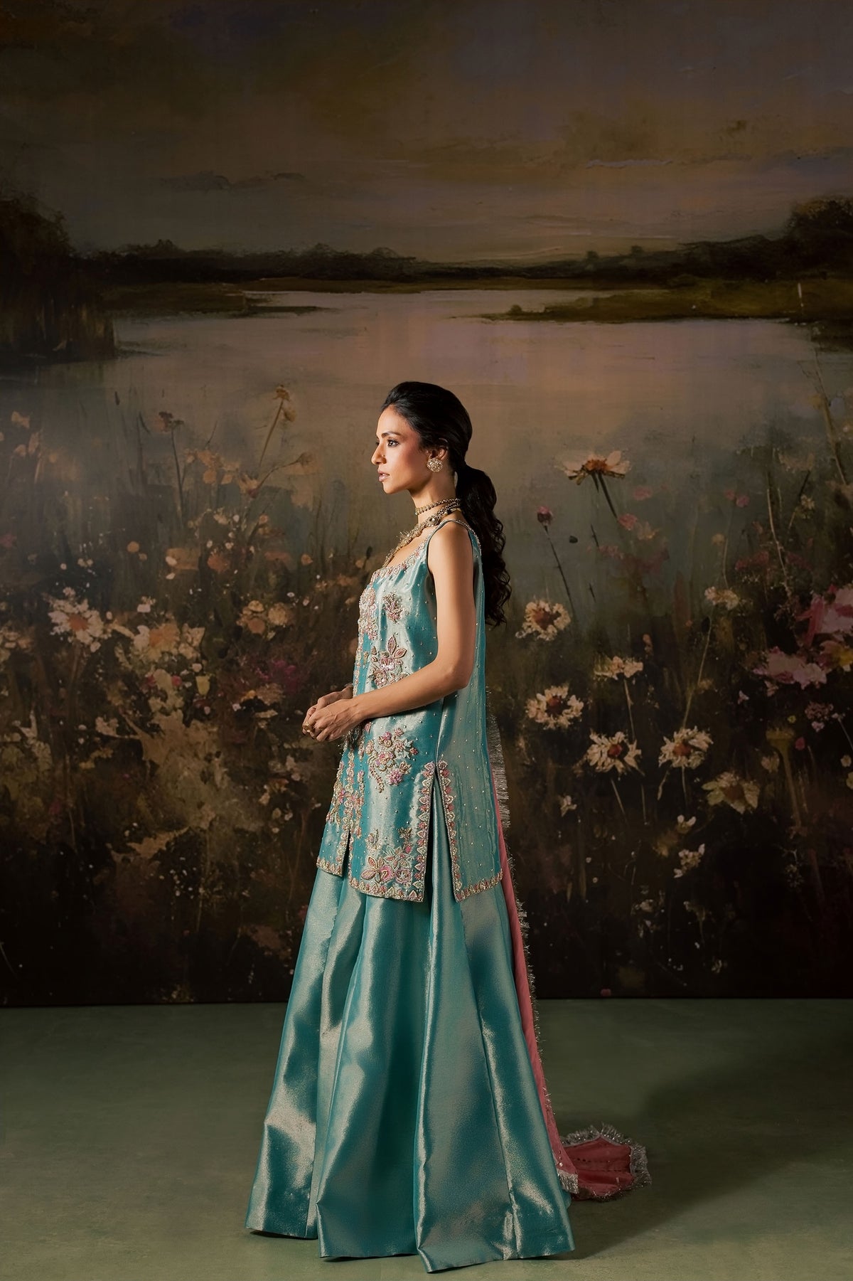 Side profile of the Zonaira Ahmed Firouzeh outfit showing the flared teal sharara silhouette and pink dupatta drape
