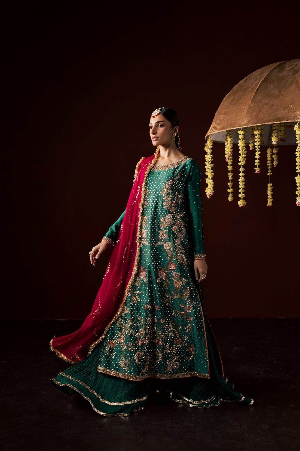 Zonaira Ahmed Haya emerald green maroon wedding formal 3-piece – full-length front view with dupatta flowing beside umbrella prop