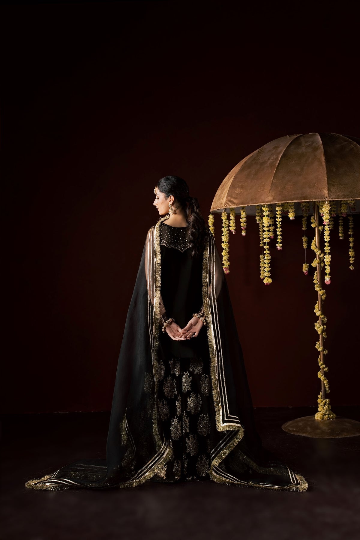 Zonaira Ahmed Laila black gold wedding formal 3-piece – full-length back view beside decorative umbrella prop