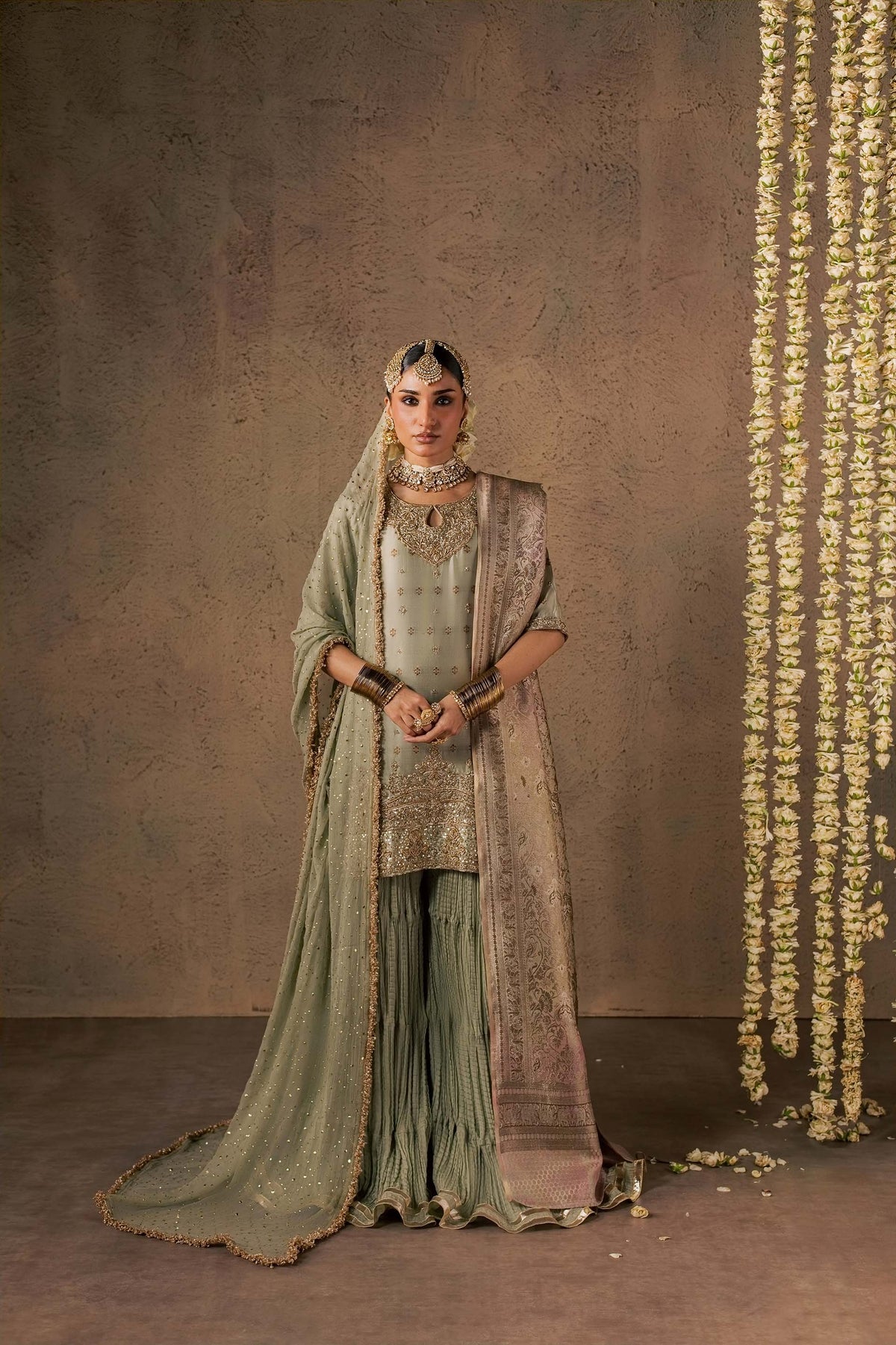 Zonaira Ahmed Naaz sage green wedding formal 3-piece – full front view with hands clasped and heavy dupatta draped over the shoulders