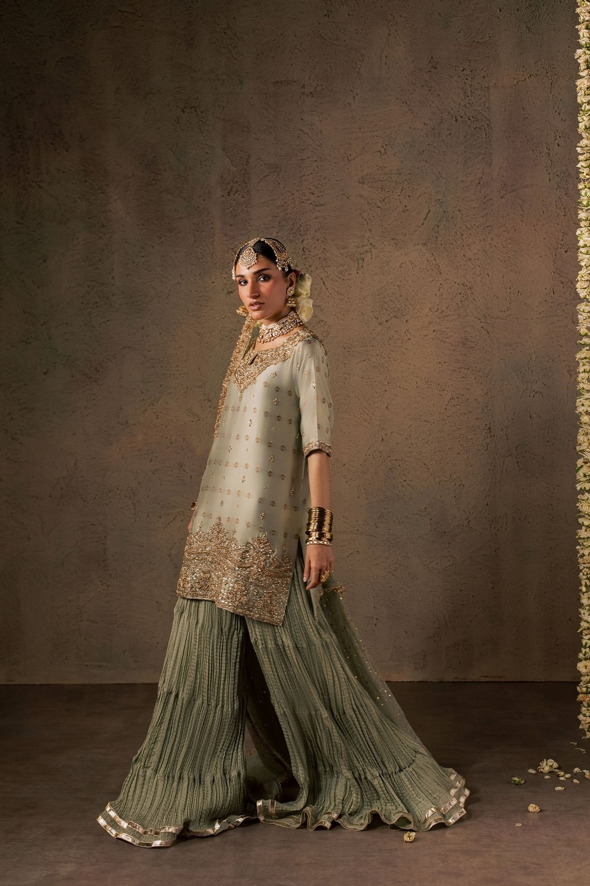 Zonaira Ahmed Naaz sage green wedding formal 3-piece – side-profile walking view showing the sharara flare