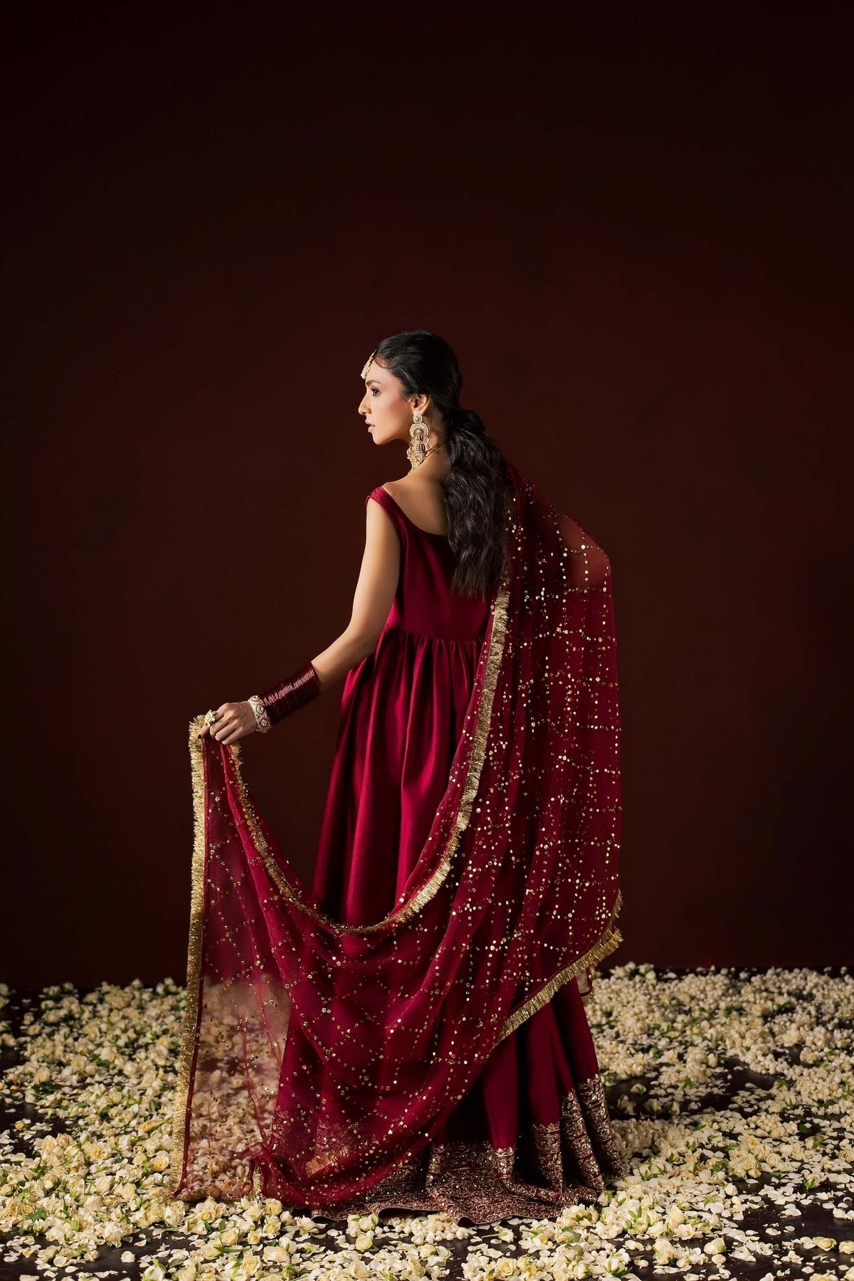 Zonaira Ahmed Neysa maroon wedding formal peshwas – back view in profile, holding the gold mukesh dupatta out to the side