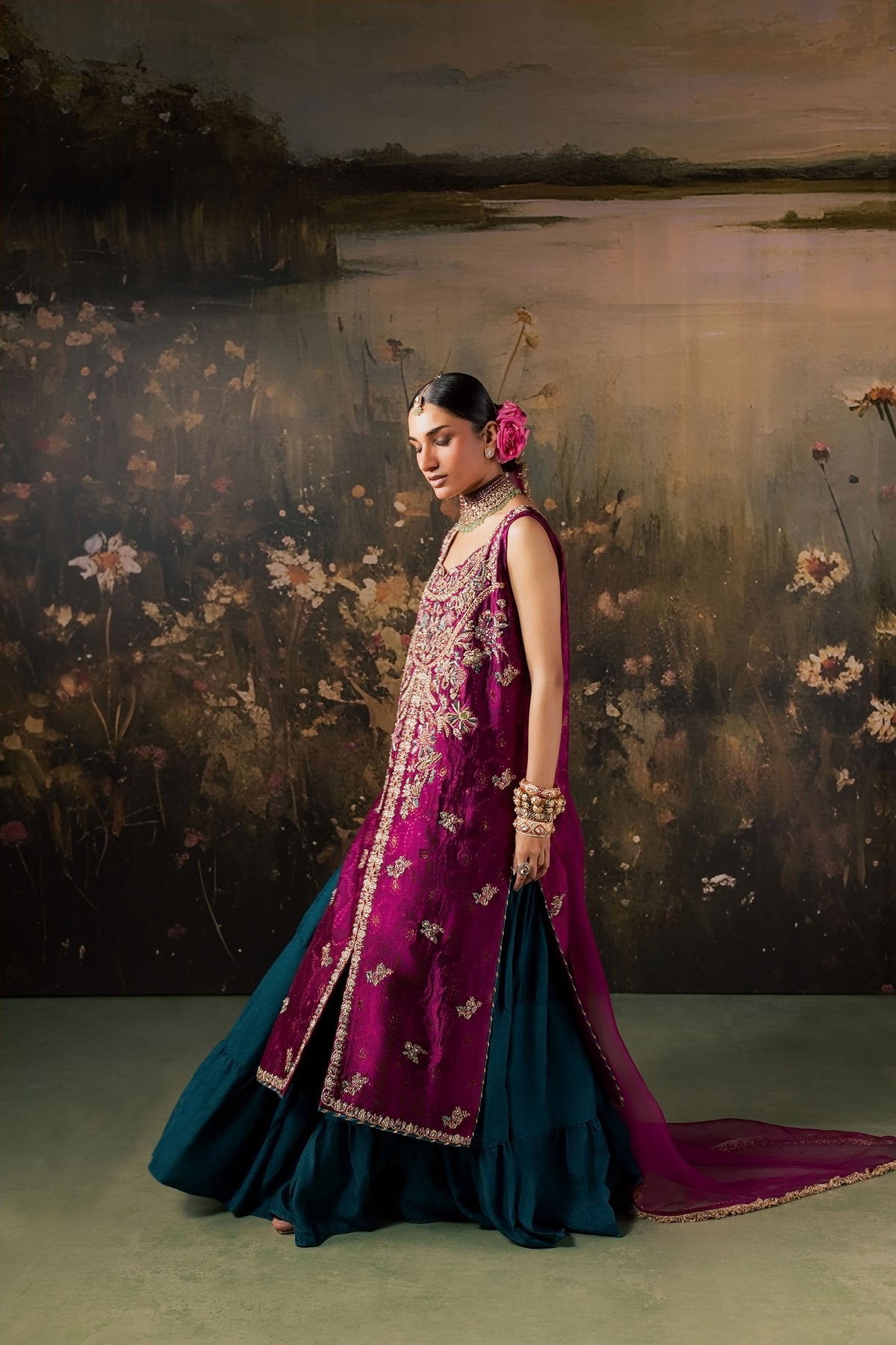 Zonaira Ahmed Rania magenta teal wedding formal 3-piece – side profile with magenta embroidered kurta and teal flared skirt, painted floral lake backdrop
