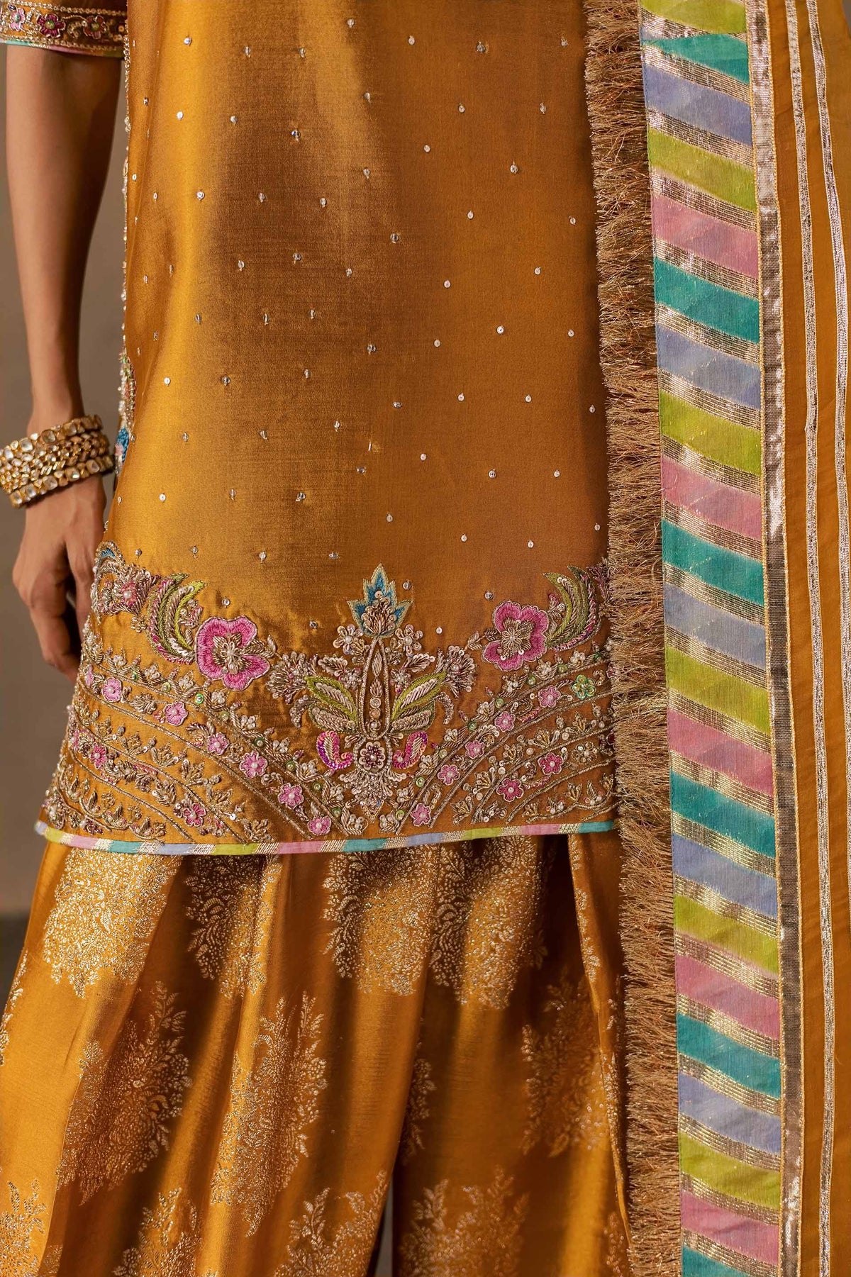 Zonaira Ahmed Zarmin mustard wedding formal 3-piece – close-up of floral hem embroidery and multicoloured striped patti border