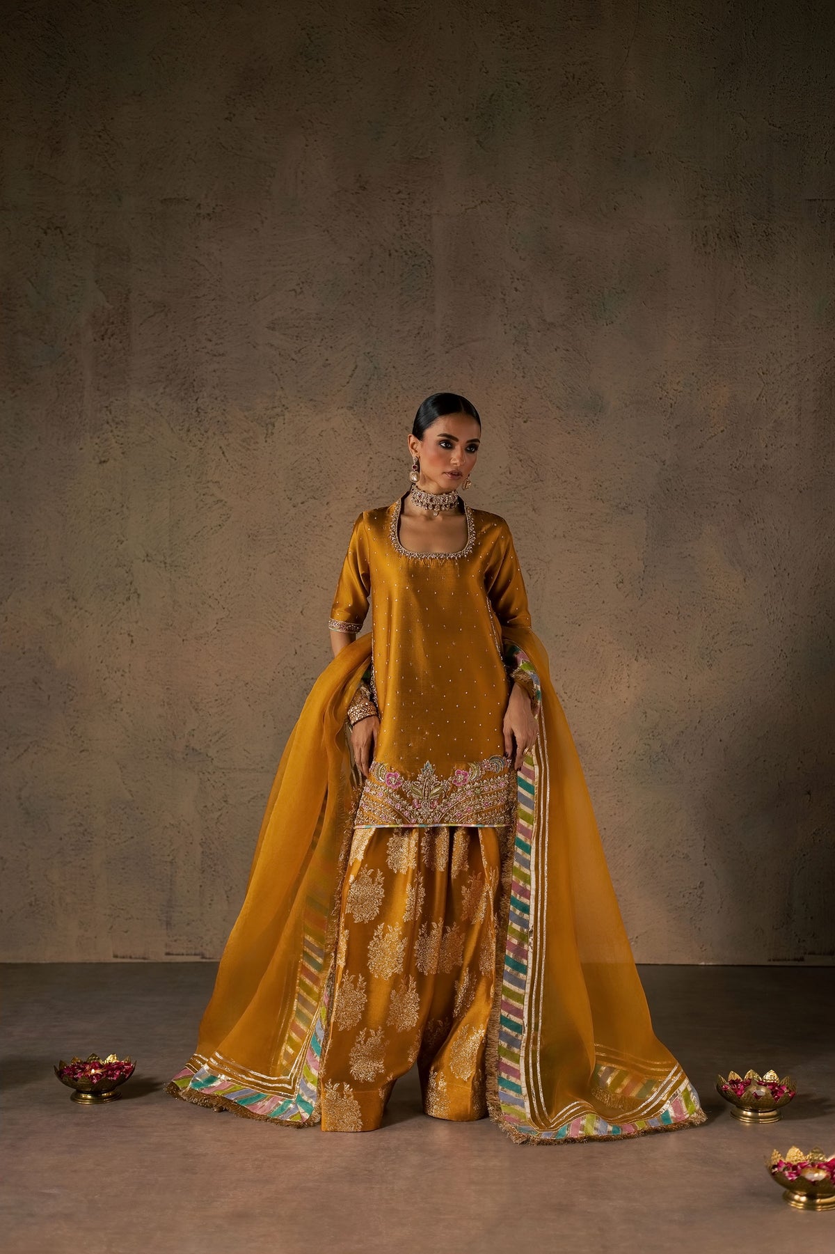 Zonaira Ahmed Zarmin mustard wedding formal 3-piece – full front view with dupatta spread wide, styled with brass diya bowls